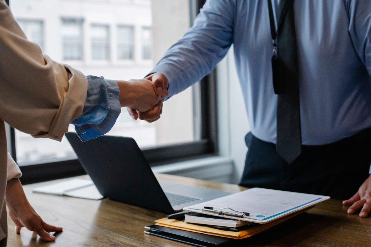 Mastering the First Impression: Your intriguing post title goes here Crop unrecognizable coworkers in formal wear standing at table with laptop and documents while greeting each other before meeting